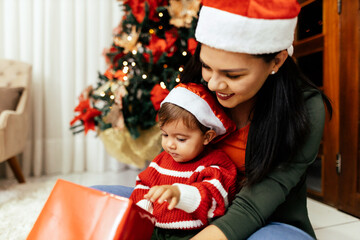 Wall Mural - Mother and her baby playing at home on Christmas holiday