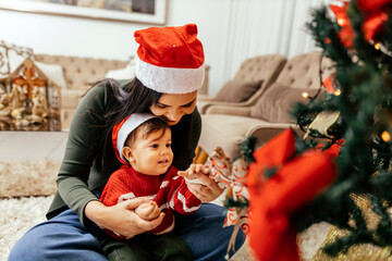 Mother with baby son dacorating christmas tree