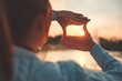 © oatawa - New year planning and vision concept, Close up of woman hands making frame gesture with sunset, Female capturing the sunrise. copy space.