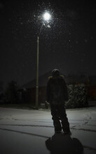 Boy Looking A Snowy Sky Under A Streetlight At Night