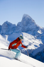 Females Skier Makes Her Way Down The Slopes Beneath The Looming Grand Teton.  Powder Spray Attests To The Great Conditions.