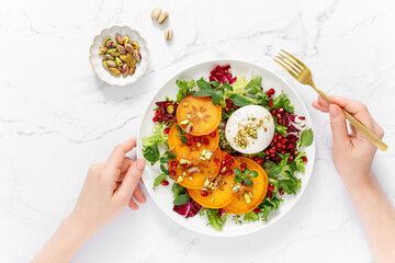 Salad with persimmon, burrata, pomegranate and pistachio, healthy food, top view