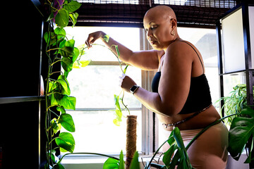 Bald Black woman taking care of plants