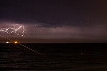 Lightning Flashed At Night In The Sky Between The Clouds On The Sea Horizon Over Two Ships Close-up	
