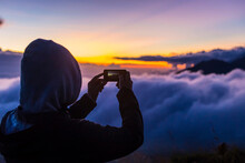 Man Takes Photos With Smartphone In Mountains At Sunrise