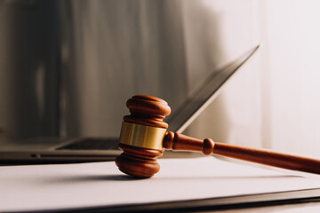 Justice and law concept.Male judge in a courtroom with the gavel, working with, computer and docking keyboard, eyeglasses, on table in morning light