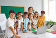 © Studio Romantic - Happy diverse elementary school students with teacher using laptop in math lesson. Portrait of joyful female teacher and school students using online software for teaching web educational technology.