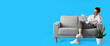 © Pixel-Shot - Pretty young woman with unusual hair reading book on sofa against blue background with space for text