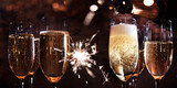 New year toasting with champagne and sparklers on dark background. Atmospheric horizontal close-up with champagne glasses for festive moments and space for text.