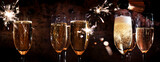 New year toasting with champagne and sparklers on dark background. Atmospheric close-up with champagne glasses for festive moments and space for text.