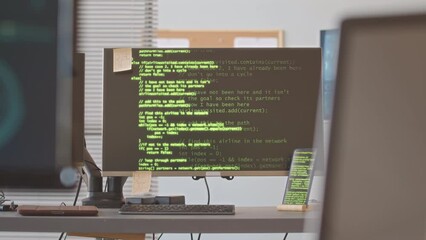 No people shot of coding lines appearing on black screen of computer monitor on desk at programmers office