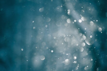 Blurred Snowflakes In Morning Light In Winter Forest. Glowing Bokeh Abstract Background.