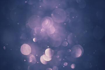 Blurred snowflakes in evening light at sunset. Colorful glowing bokeh abstract background.