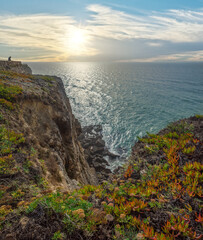 Wall Mural - rocky coastline, ocean and sunlight shines through gaps in clouds. beautiful nature background.