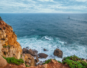 Wall Mural - beautiful cloudy sky and foaming waves approaching rocky shore of the atlantic ocean. beautiful natu