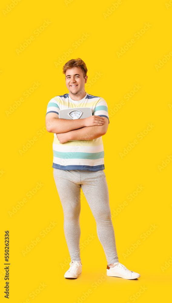 Young overweight man with scales on yellow background
