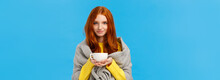 Redhead Girl Trying Get Warm, Feeling Cold Wrapping Herself With Scarf On Shoulders, Drinking Hot Tea, Holding Teapot And Smiling Lovely, Standing Tender And Cute Blue Background