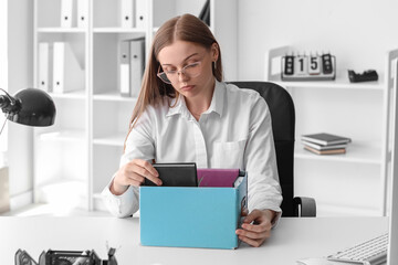 Wall Mural - Fired young woman packing her personal stuff in office