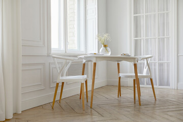 Interior of contemporary light room with white walls and big windows round table with two chairs and glass vase on it