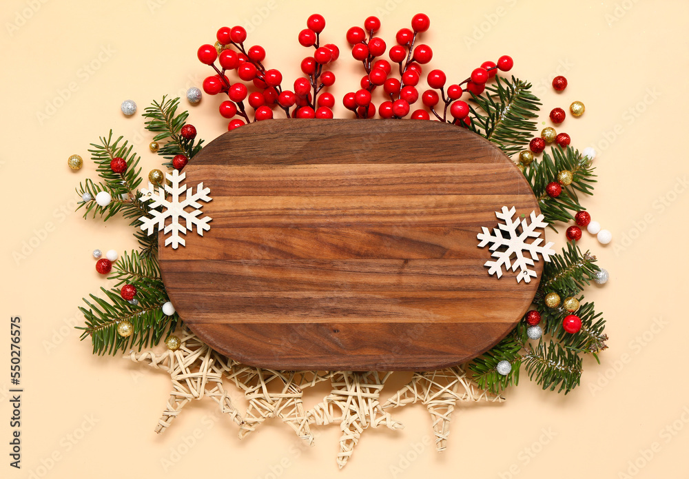Composition with wooden cutting board, fir branches and Christmas decorations on color background