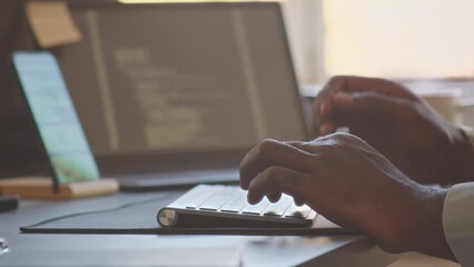 Closeup of unrecognizable male hands of programmer typing program code on wireless keyboard while working in office