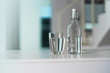 Wall Mural - A glass of clean drinking water and a water bottle On a white wooden table