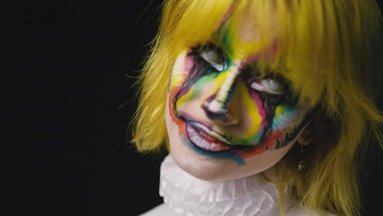 Wall Mural - Young girl with clown face art, lady with colorful make up turned face to camera, halloween theme