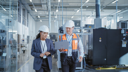 Poster - Professional Heavy Industry Employees Wearing Hard Hats at Factory. Checking and Discussing Industrial Facility, Working on Laptop Computer. African American Engineer and Asian Technician at Work.
