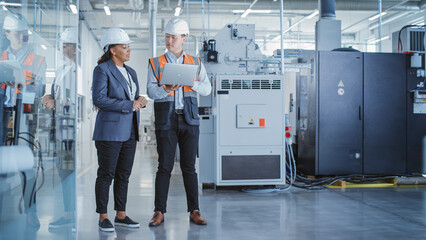 Aufkleber - Two Professional Heavy Industry Colleagues in Hard Hats at Factory. Checking and Discussing Industrial Facility, Working on Laptop Computer. African American Engineer and Asian Technician at Work.