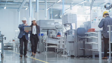 Poster - Two Diverse Heavy Industry Engineers in Hard Hats Walking with Laptop Computer and Talking in a Factory. Footage of Two Manufacturing Employees at Work.