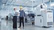 © Gorodenkoff - Two Heavy Industry Employees in Safety Uniform and Hard Hats Walking and Talking in a Factory. Asian Engineer and Technician are Discussing Industrial Machine Facility, Using Laptop Computer.