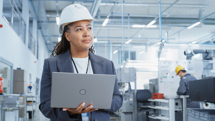 Poster - Black African Female Engineer in Hard Hat Standing and Using Laptop Computer at Electronic Manufacturing Factory. Technician Working on Daily Tasks and Research and Development Data.