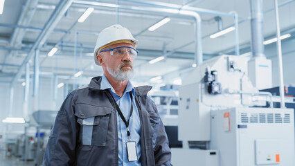 Wall Mural - Portrait of a Middle Aged, Successful Male Engineer Putting On a White Hard Hat and Safety Glasses, While Walking at Electronics Manufacturing Factory. Heavy Industry Specialist Posing for Camera.