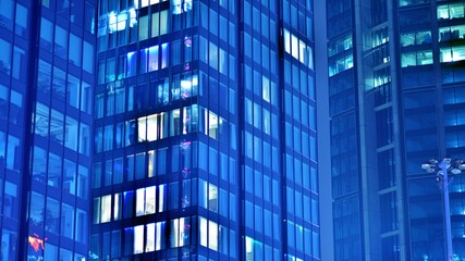 Wall Mural - Pattern of office buildings windows illuminated at night. Glass architecture ,corporate building at night - business concept. Blue graphic filter.