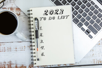 To Do List 2023 text on notepad with laptop on wooden background