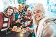 © Davide Angelini - Happy friends celebrating Christmas and new year eve party together - Cheerful young people holding wine glasses taking selfie picture sitting at bar restaurant - Beverage and winter holiday concept
