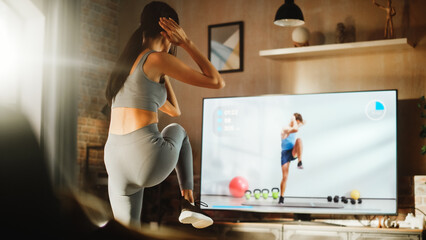 Home Training: Beautiful Girl Training with Personal Trainer via Online Video App. Authentic Athletic Woman Using Workout Service in Fitness Streaming App for Virtual Training. Healthy Girl Exercises