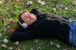 © ADDICTIVE STOCK - Happy female in headphones lying on grass