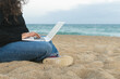 © ADDICTIVE STOCK - Anonymous woman using laptop on beach