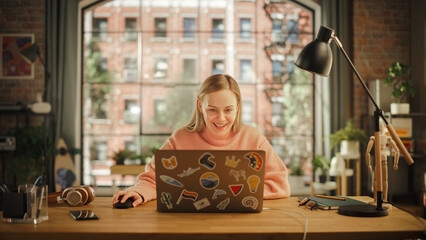 Poster - Happy Young Woman Working on Laptop Computer while Sitting in Stylish Creative Office. Successful Freelancer Receiving New Order and Celebrating. Female Winning Lottery and Expressing her Joy.