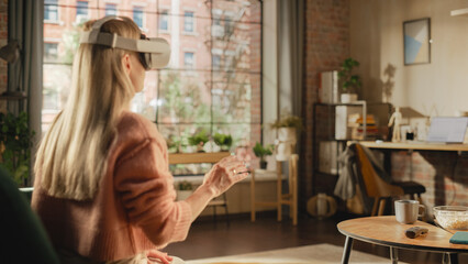 Poster - Over the Shoulder Footage of a Female Freelancer Using Virtual Reality Headset and Controllers for Her Project while Sitting on a Couch. Young Woman Working in Futuristic Metaverse App.