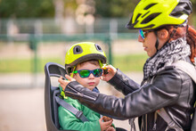 Mother Clasping Sons Helmet Before Riding Bicycle