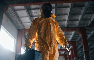 Wall Mural - Walking with hard case. Man dressed in chemical protection suit in the ruins of the post apocalyptic building