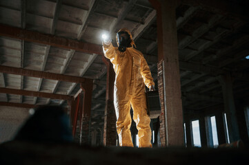 Wall Mural - Using the flashlight. Man dressed in chemical protection suit in the ruins of the post apocalyptic building