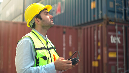 Wall Mural - Logistic staff flying drone to survey and inspect stack container in shipment company area.