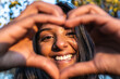 © Vittorio Gravino - Frontal view of happy woman laughing at camera and making a heart shape with hands .