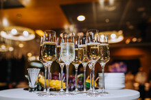Glass Wine Glasses With Champagne, Sparkling Drink Stand On A Round White Table With Fruits And Dishes In A Restaurant. Photography, Banquet, Wedding.