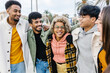 Multiracial young friends having fun in city street. United millennial people hugging each other standing together outdoors. Multi-ethnic friendship and youth concept