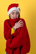 © andyborodaty - Young positive woman in christmas santa hat isolated on yellow background. Happy young woman in Santa's helper hat.