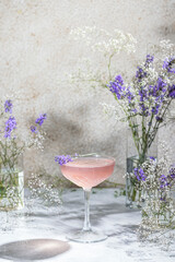 Wall Mural - Elegant glass of Lavender Cocktail or mocktails surrounded by ingredients and fresh lavender and gypsophila flowers on gray table surface